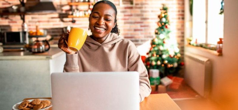 A woman holding a mug while looking at her laptop